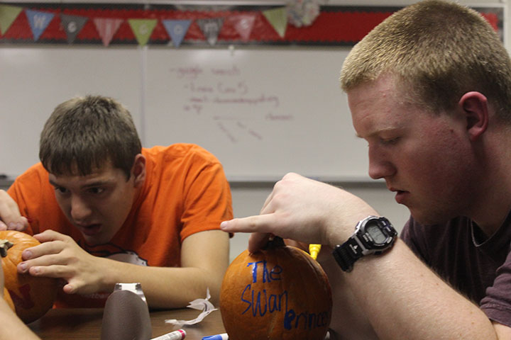 Sophomore Brook Chromy and junior Tyler Rossell paint pumpkins during the Circle of Friends meeting.  Chromy, an avid Husker fan, printed out decals to help him get the design perfect. 