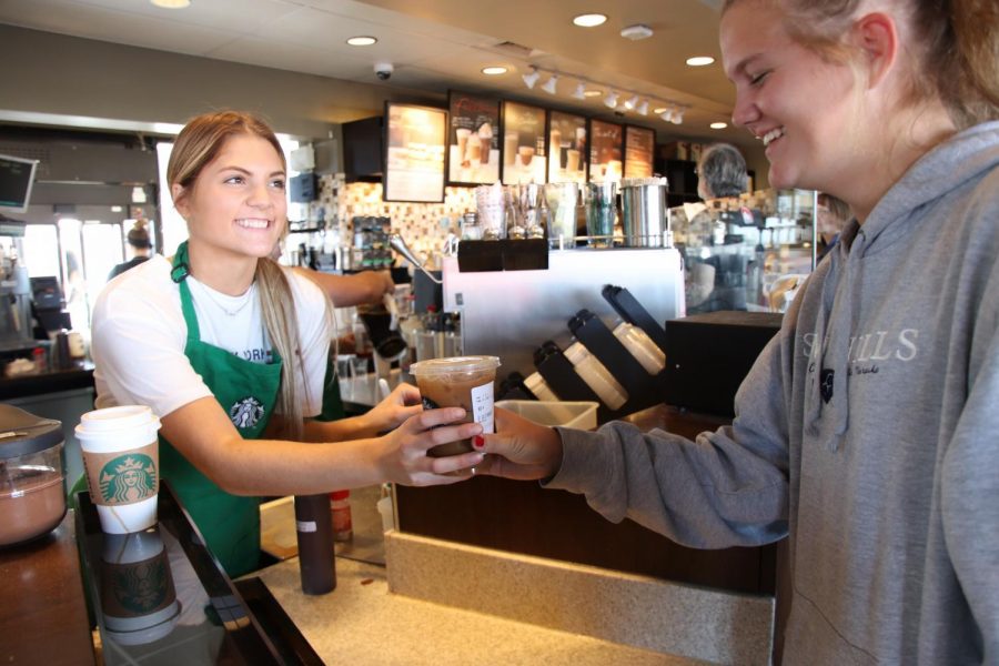 Starbucks barista Emily Hendren hands sophomore Maya Lashley her coffee.I think theres always a lot [of highschoolers] and theres a big rush before school, said Hendren. 
