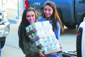 Seniors Alecea Comer (left) and Aniston Manzano unload cans during the “senior parade” at the NPHS canned food drive on Nov. 16.