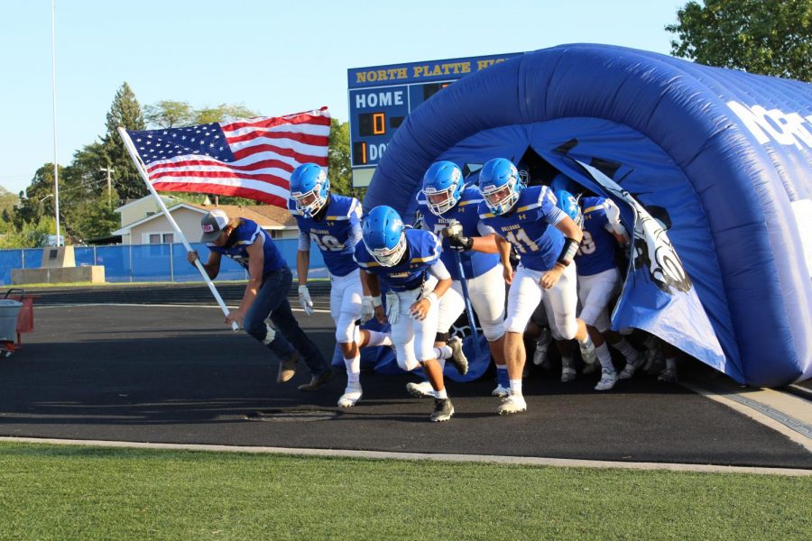 The Bulldogs Varsity Football team runs onto the field to kick off the game. 
