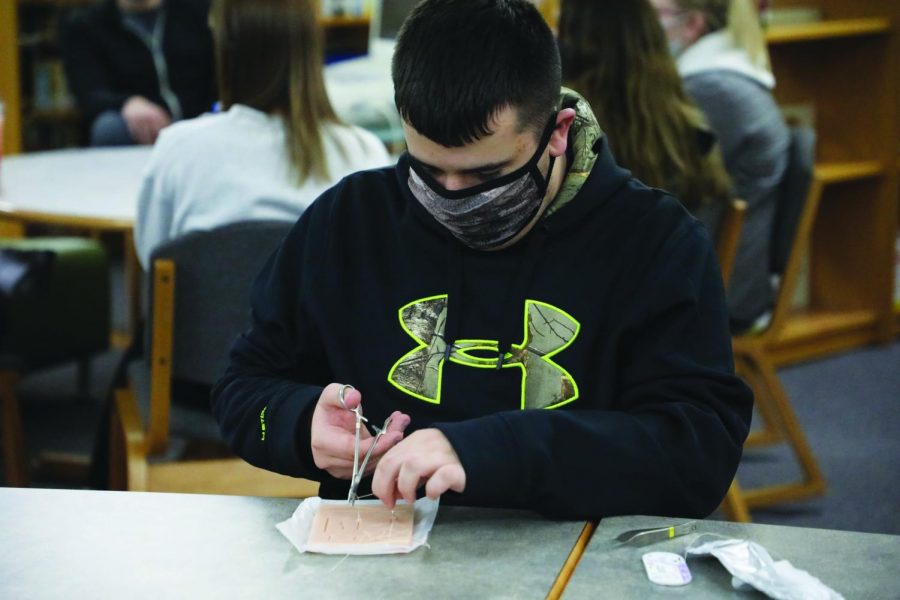 Sophomore Kaden Gilbert practices stitching and suturing during medical club