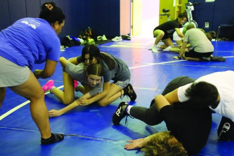 Girls’ wrestling co-coach Cheryl Hall, left, looks on as boy wrestlers Hayden Brauer, right, and Kole Weigel show girls Brooklyn Brown and Monica Charging Elk a move during open mat practice in early November.