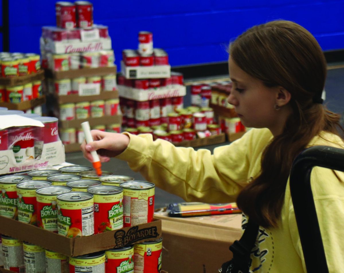 Kenedi Schroeder sorts items for the canned food drive. 